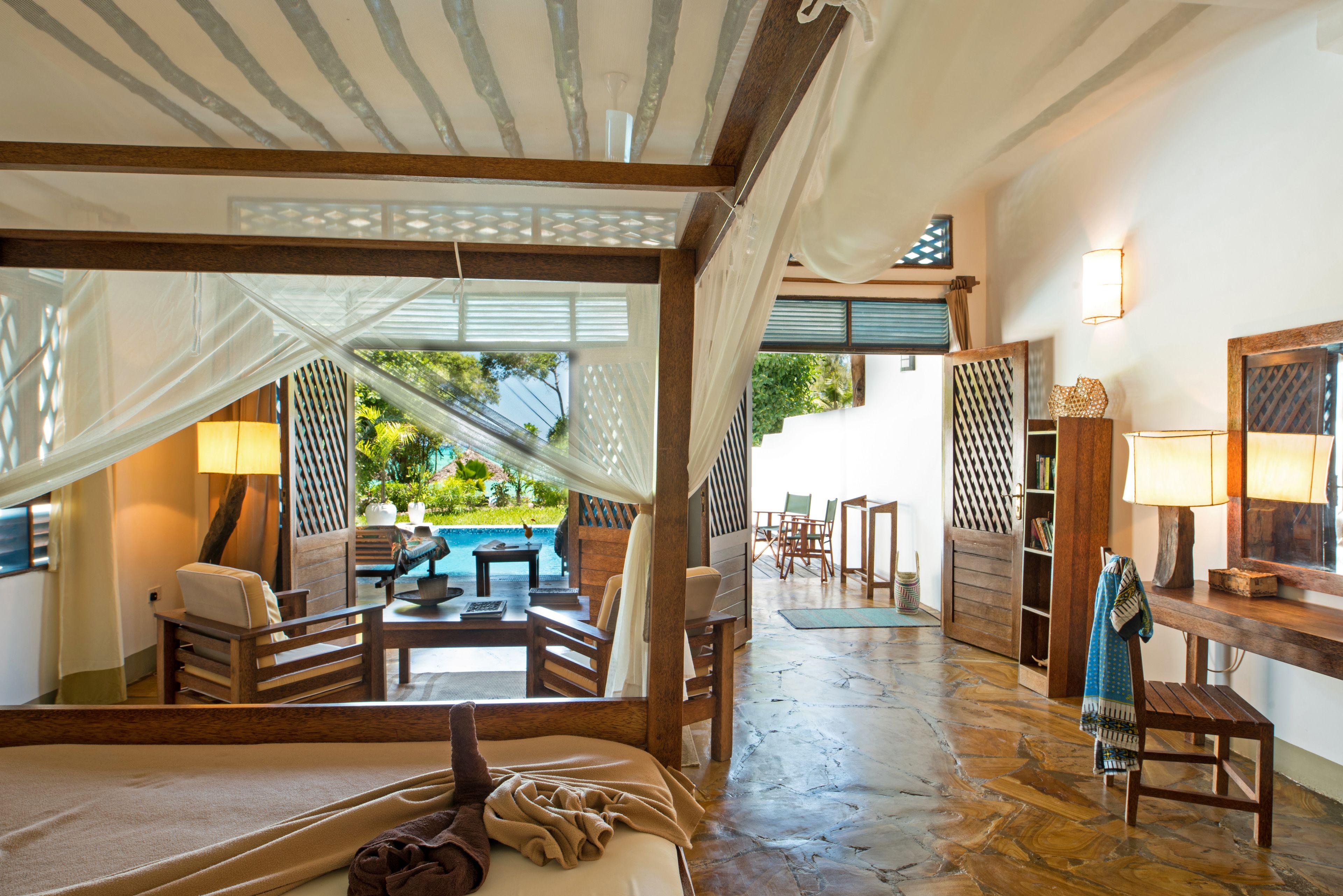 A room with a bed, a view of an outdoor pool, and a wooden floor.
