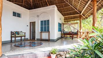 A spacious room with a tiled floor, a wooden bench, a small table, and a potted plant.