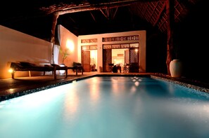 Relax by the serene pool surrounded by a wooden deck and elegant decor.