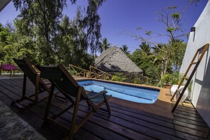 Relax by the serene pool surrounded by lush greenery and comfortable deck chairs.