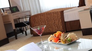 A hotel room with a bed, a desk, a laptop, a martini glass with fruit, and a plate of fruit on a table. - Rescate Boutique Hotel Ankara (Ankara)