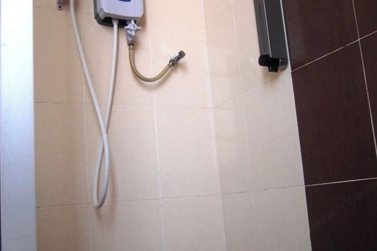 A shower area with a control panel and a hose.