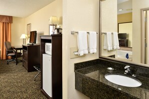 Habitación de hotel con escritorio, silla y minibar.