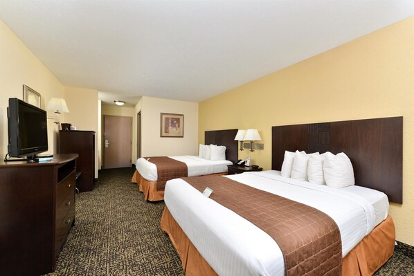 A hotel room with two beds, a television, a desk, and a lamp.