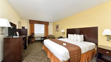 Een hotelkamer met een groot bed, een bureau met een computer, een stoel en een kleine tafel.