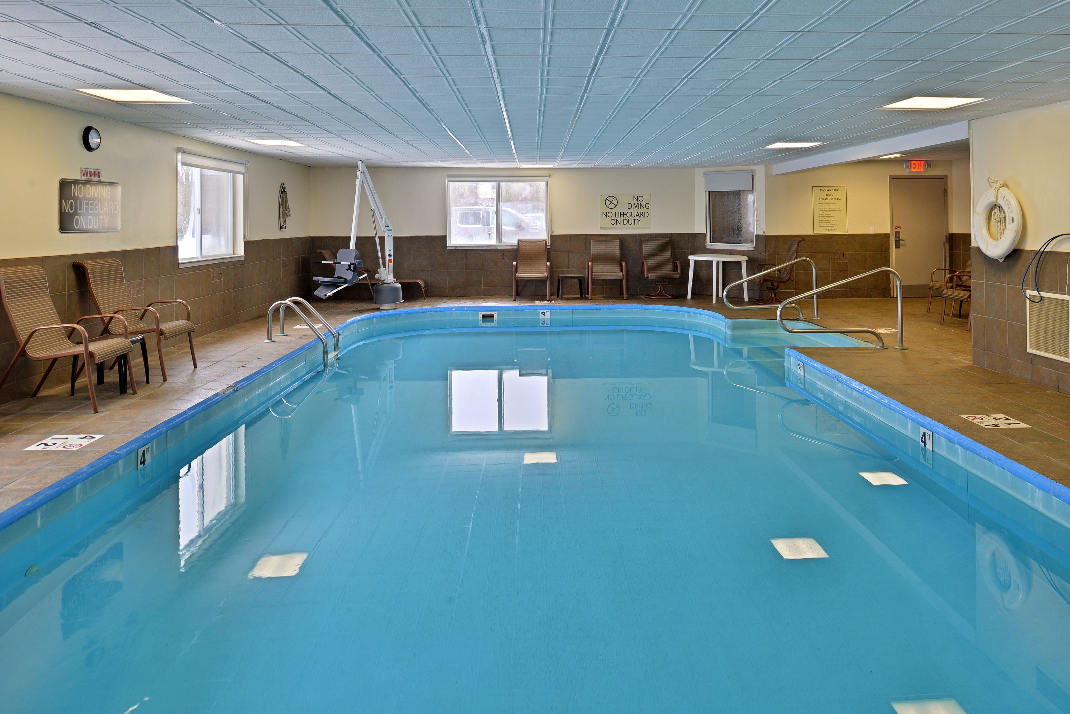 An indoor swimming pool with clear lane markings, a lifeguard chair, and a no diving sign.