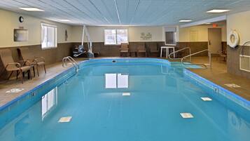 An indoor swimming pool with clear lane markings, a lifeguard chair, and a no diving sign.