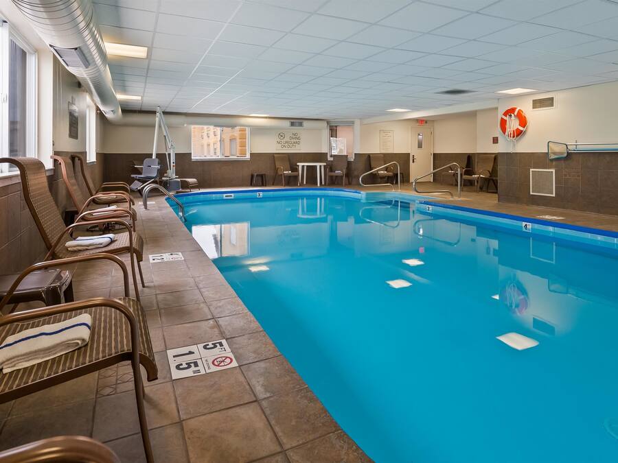 Un área de piscina con sillones de descanso, un letrero de salvavidas y un aviso de no buceo.