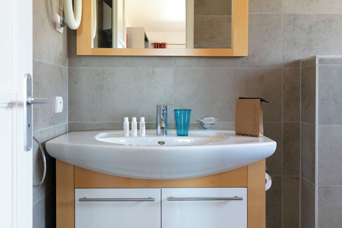 A bathroom with a white sink, a mirror above it, and a wooden cabinet below.