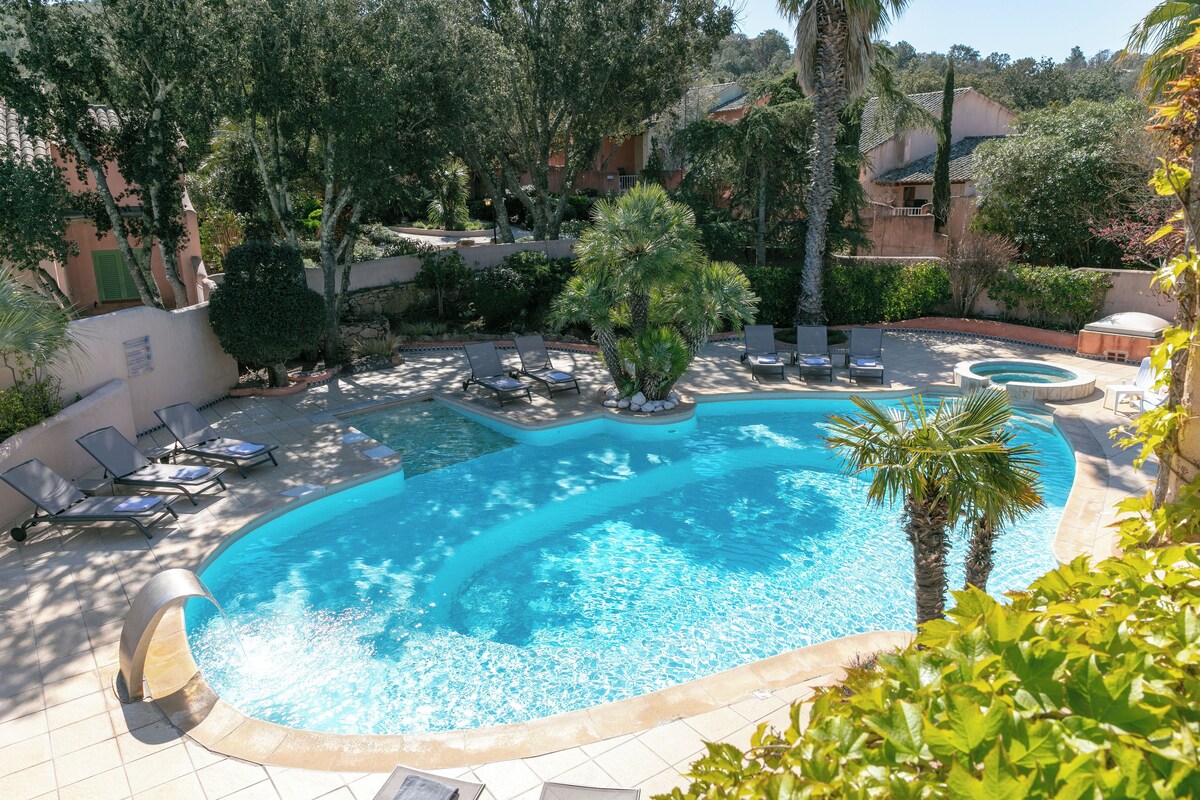Une piscine avec des chaises longues et un palmier.