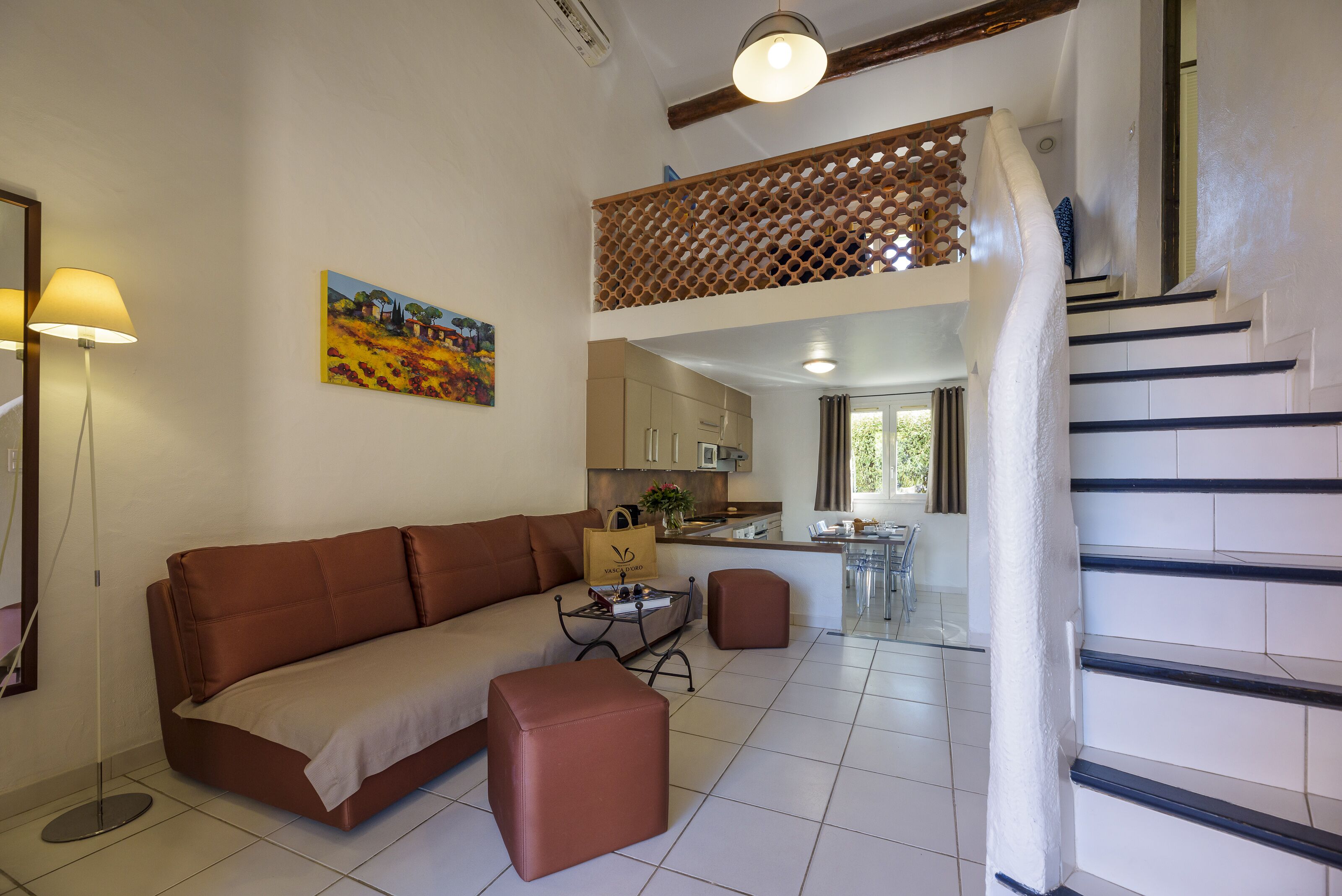 A modern living room with a sofa, ottoman, and a dining area with a table and chairs.