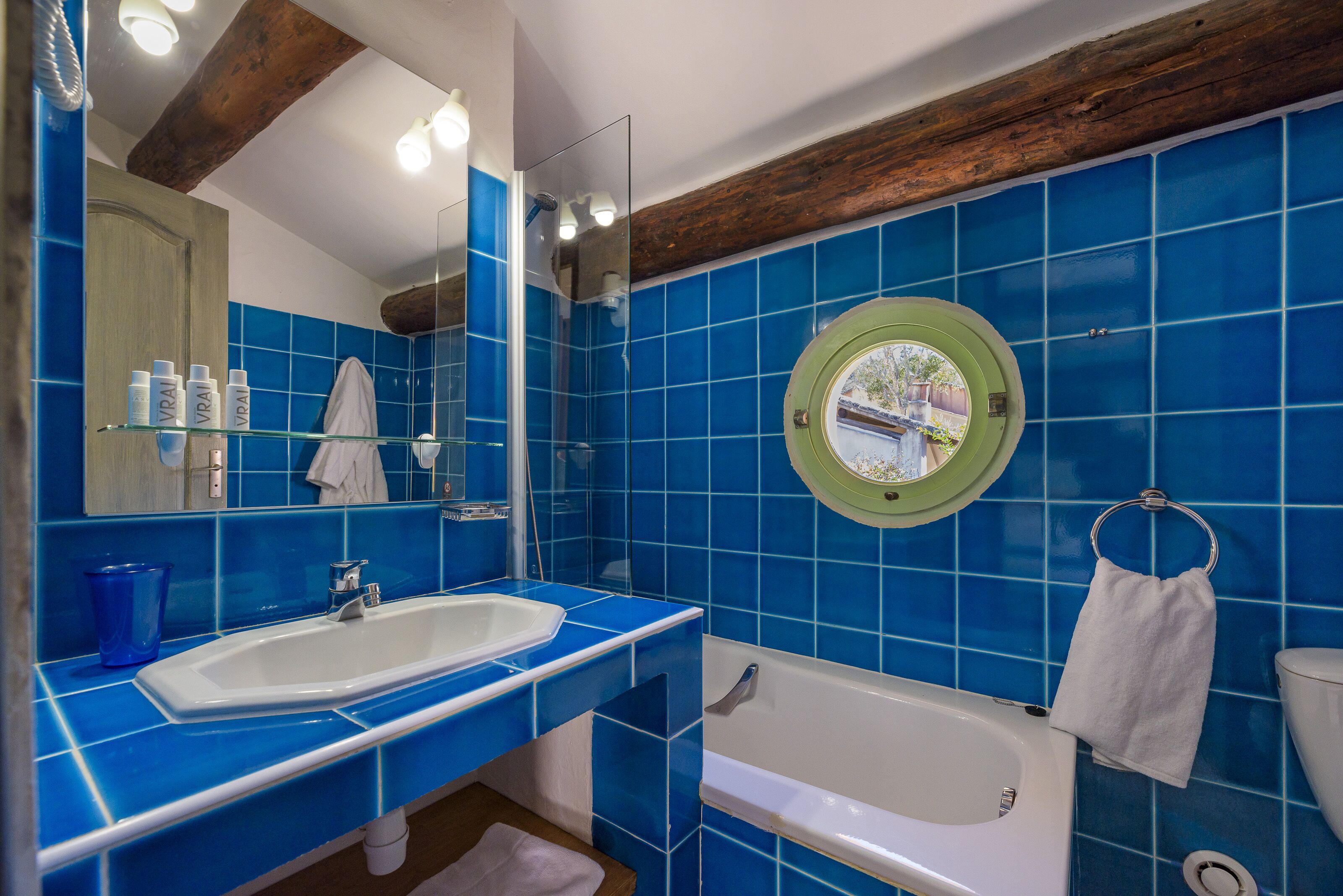 A bathroom with a white sink, a bathtub, and blue tiles.