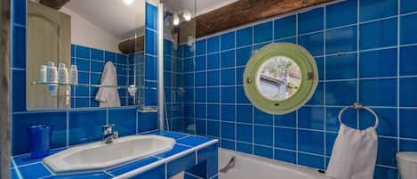 A bathroom with a white sink, a bathtub, and blue tiles.