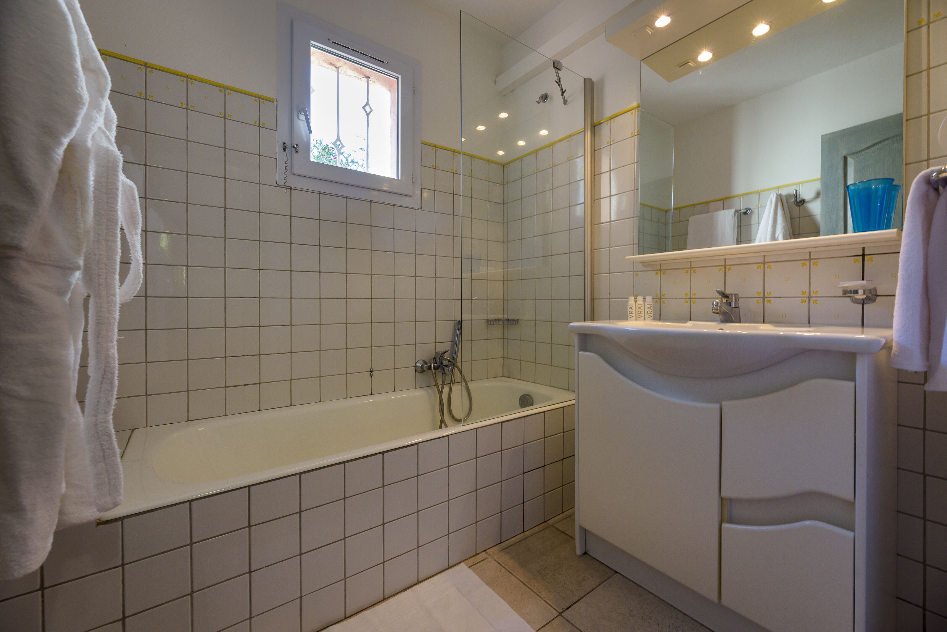 Un baño con bañera, ventana, espejo y lavabo.