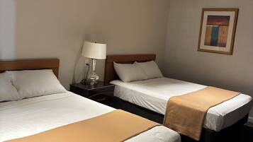 Habitación de hotel con dos camas, una mesita de noche con lámpara y un cuadro en la pared.