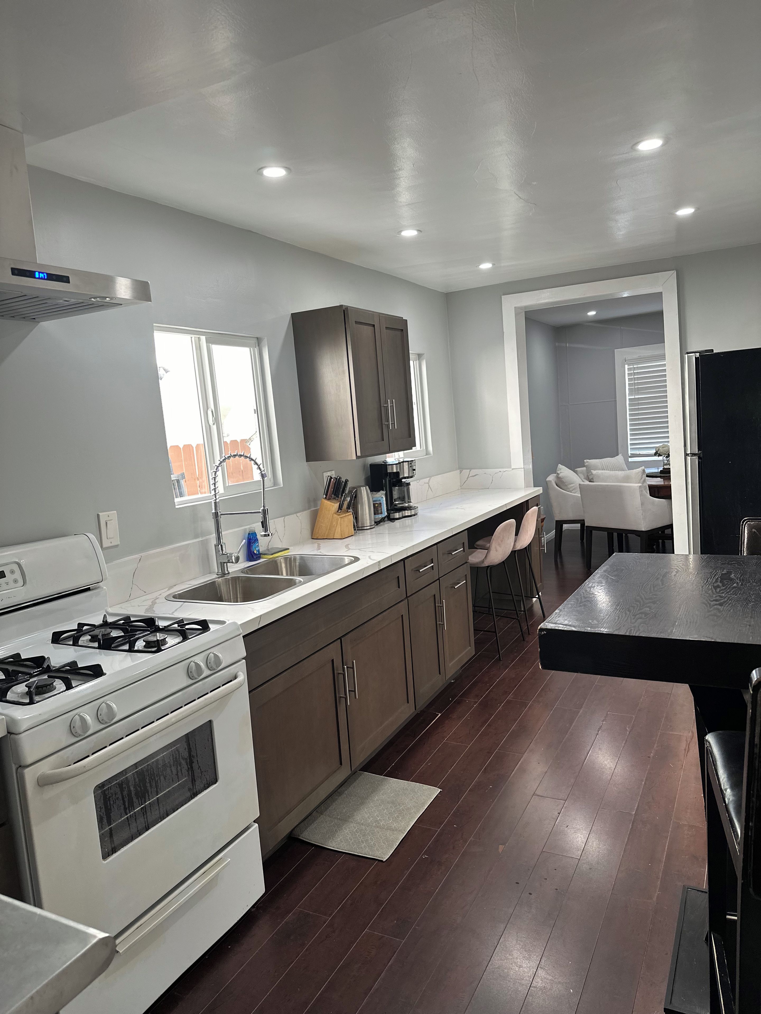 A modern kitchen with a gas stove, stainless steel sink, and dark wooden cabinets.