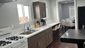 A modern kitchen with a gas stove, stainless steel sink, and dark wooden cabinets.