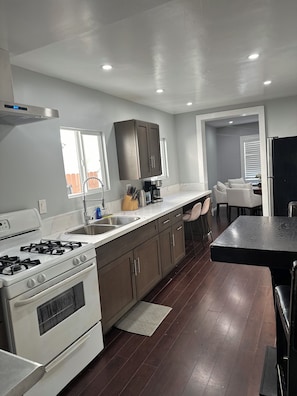 A modern kitchen with a gas stove, stainless steel sink, and dark wooden cabinets.