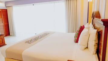 A hotel room with a large bed, a wooden headboard, and a window with curtains.