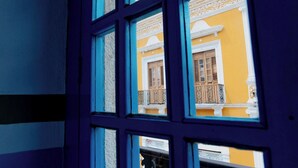 A window with a view of a yellow building with balconies. - Hotel Plaza Colonial (Campeche)