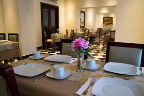 Comedor de hotel con mesas dispuestas para una comida, incluyendo platos, vasos y cubiertos.