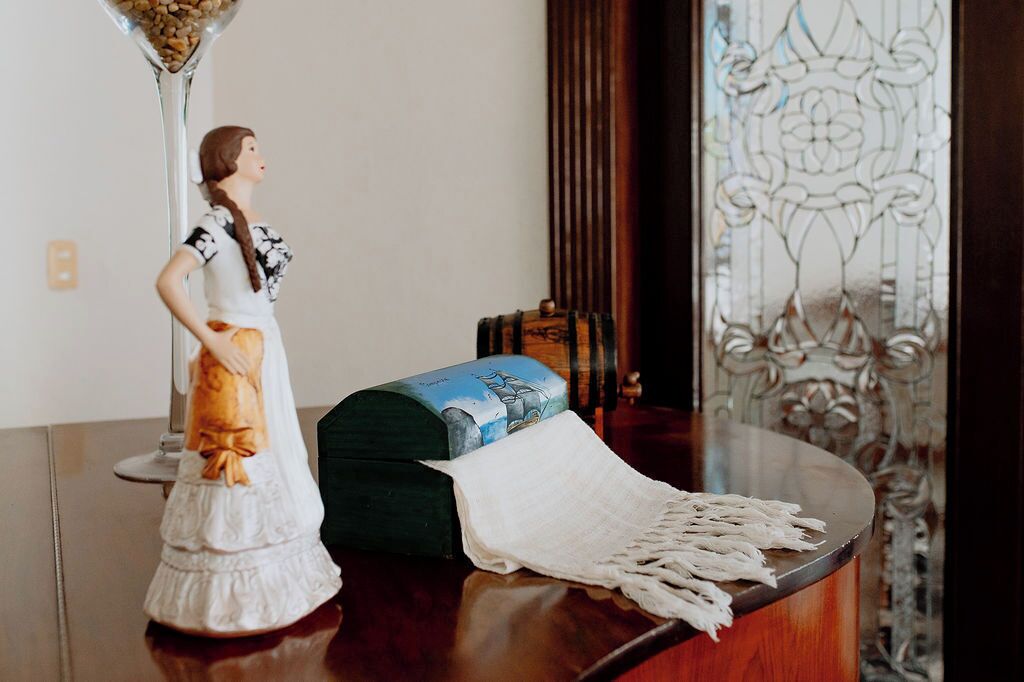 Una figurita, una lámpara decorativa y un objeto tejido sobre una superficie de madera.