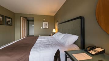 Ein Hotelzimmer mit einem großen Bett, einem Schreibtisch mit Telefon und gerahmten Bildern an den Wänden.