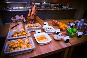 Un bufé con diversos alimentos, como pan, pasteles, frutas y salsas.