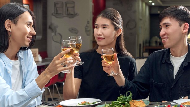 Three people toasting with wine glasses at a table with various dishes. - ibis Astana (Astana)