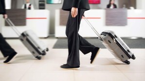 A person walking with a suitcase in an indoor setting with a reception desk and a television in the background. - ibis Astana (Astana)
