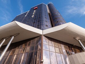 Un edificio moderno con ventanas de vidrio reflectante, un logotipo rojo llamativo y un alero blanco.