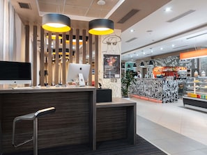 Un intérieur moderne comprenant un comptoir d’accueil, un bar à café et un grand écran.