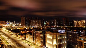 Un paisaje urbano nocturno con edificios iluminados, incluyendo el destacado Centro Silk Way.