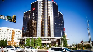 Un hotel moderno con una llamativa torre cilíndrica central, varios pisos y una entrada destacada.