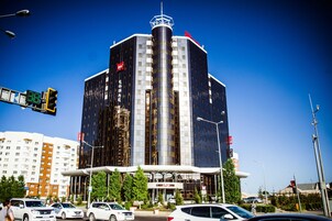 Un hotel moderno con una llamativa torre cilíndrica central, varios pisos y una entrada destacada.
