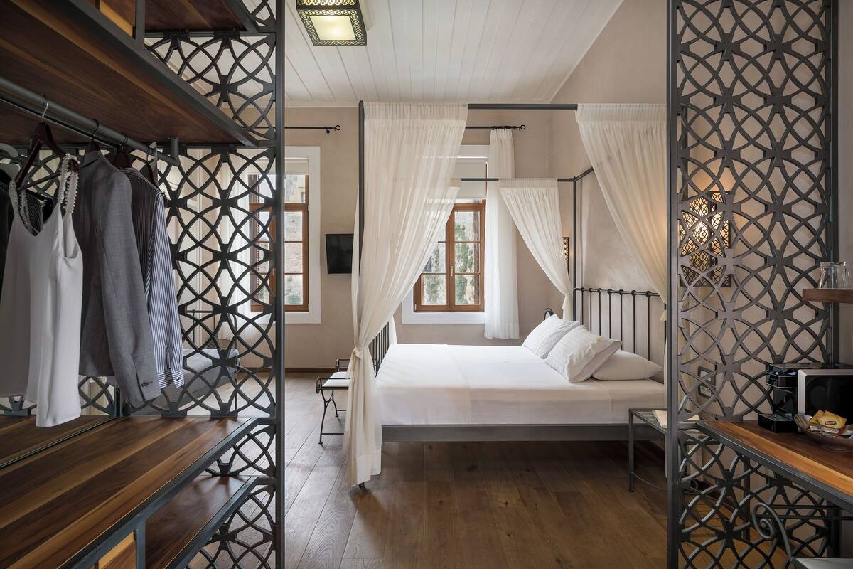 A bedroom with a bed, wooden furniture, and a decorative metal partition.