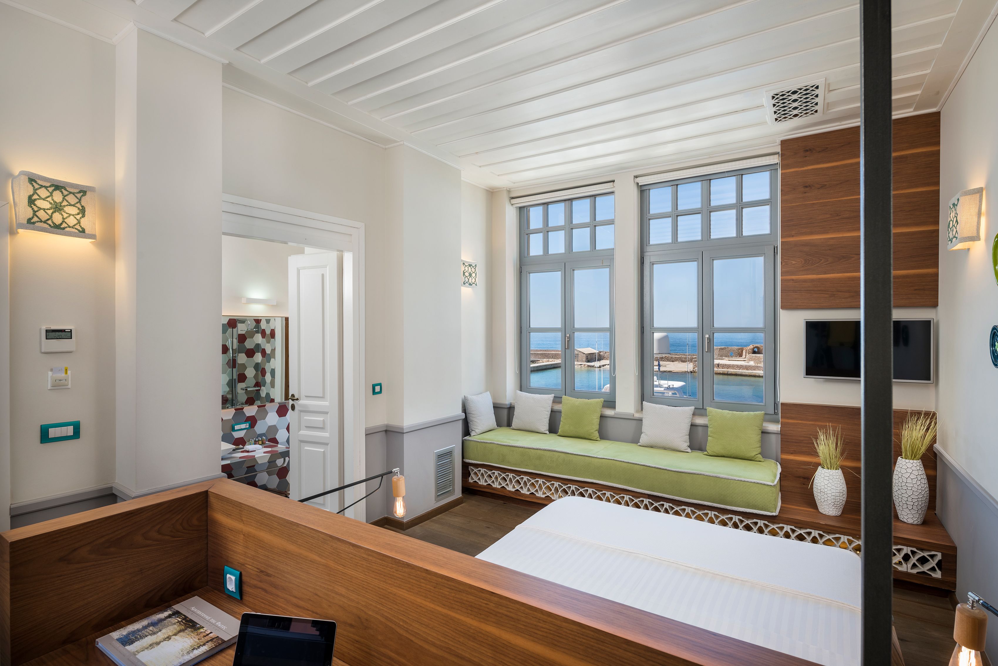 A hotel room with a large bed, a seating area by the window, and a view of the sea.