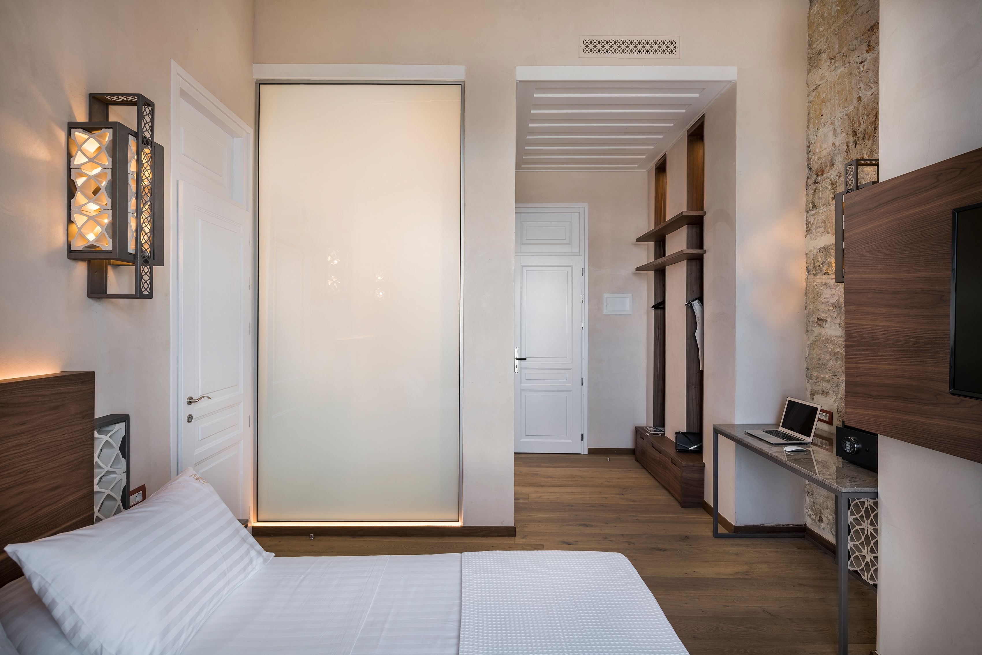Una camera da letto con un letto, una scrivania con un portatile, una televisione e un armadio con ante scorrevoli.
