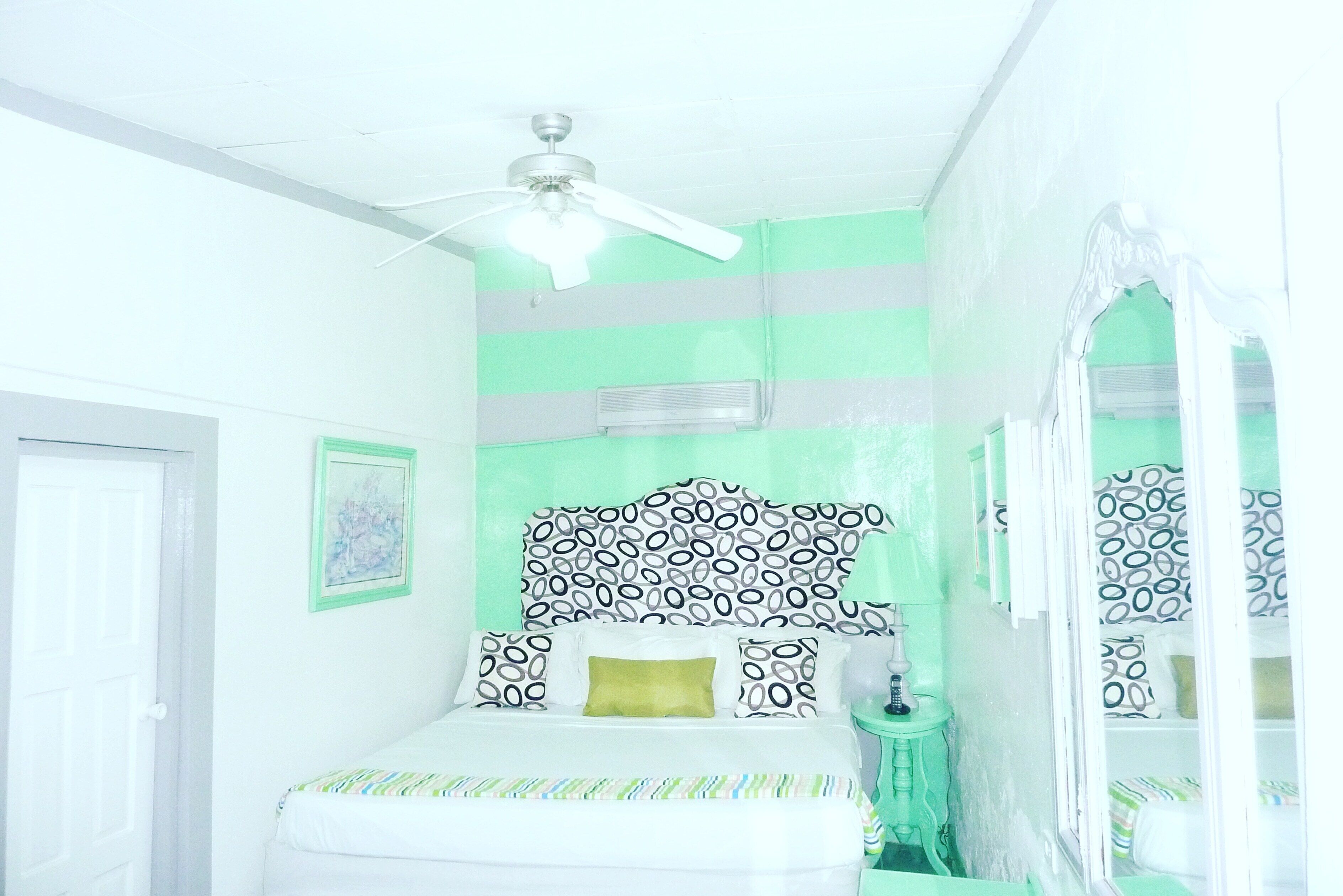 A bedroom with a bed, a ceiling fan, a bedside table, and a window.