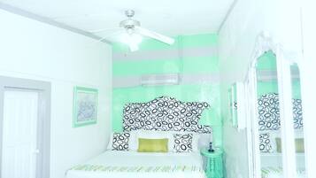 A bedroom with a bed, a ceiling fan, a bedside table, and a window.