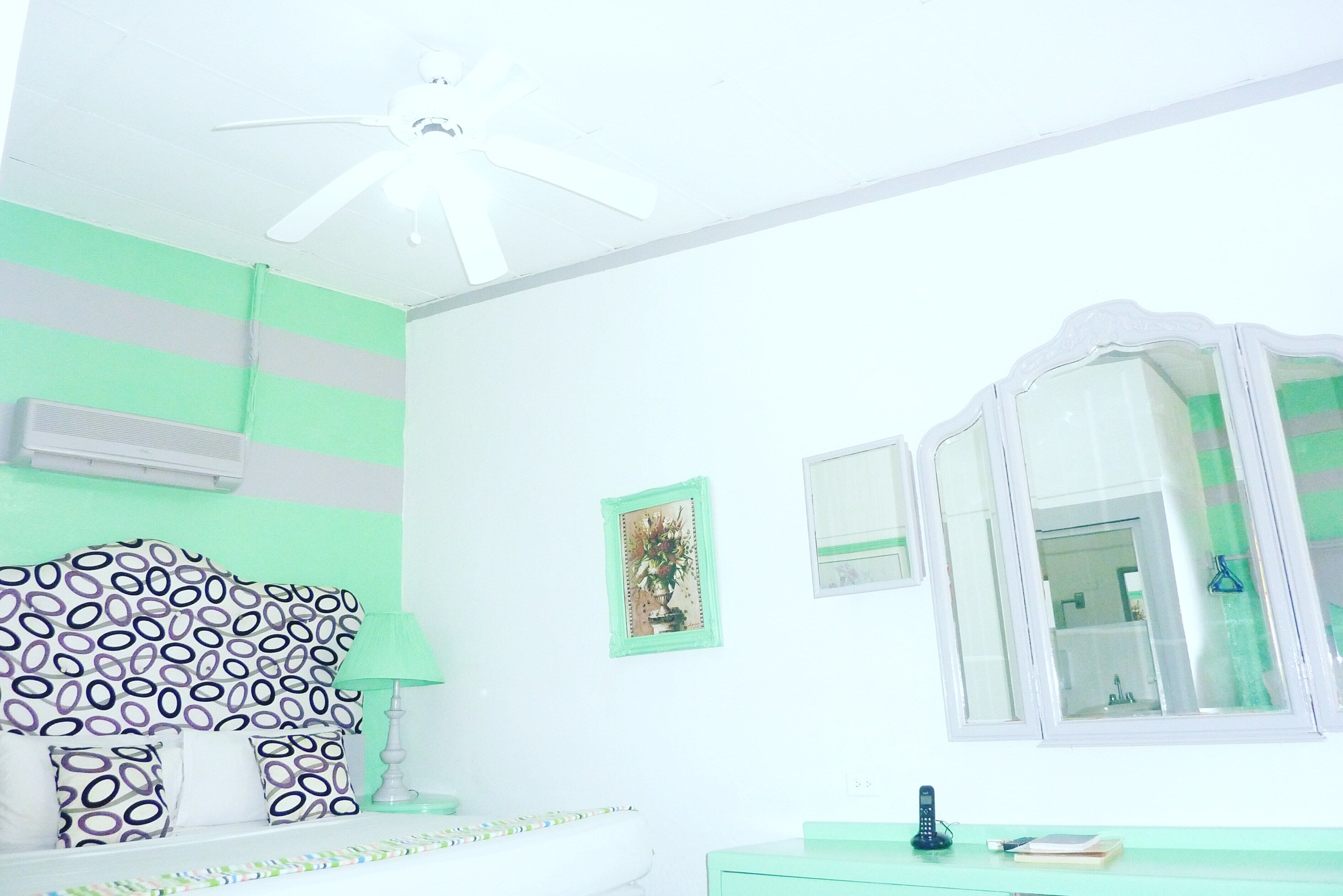 A room with a bed, a bedside table, a mirror, and a window.