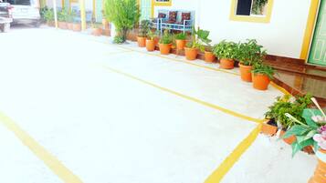 A clean, well-maintained hotel entrance with a tiled floor, potted plants, and a blue bench.