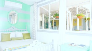 A room with a bed, a desk, a window with plants, and a view of the outside. - Hotel Ivania's (Masaya)