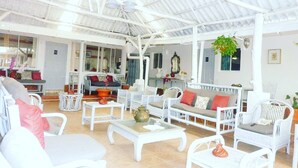 A spacious indoor area with white wicker furniture, a glass coffee table, and a ceiling with a metal framework. - Hotel Ivania's (Masaya)