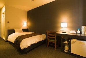 A hotel room with a bed, desk, chair, and a small refrigerator. - Hotel Taisei Annex (Kagoshima)