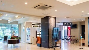 Een ruime lobby met een modern design, met een receptiebalie, zithoek en een groot raam met uitzicht op de omgeving.