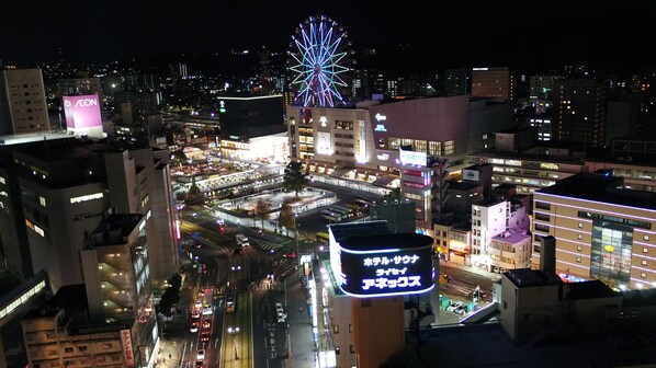 Une vue nocturne d’une ville, avec une grande roue bien visible et des bâtiments illuminés.