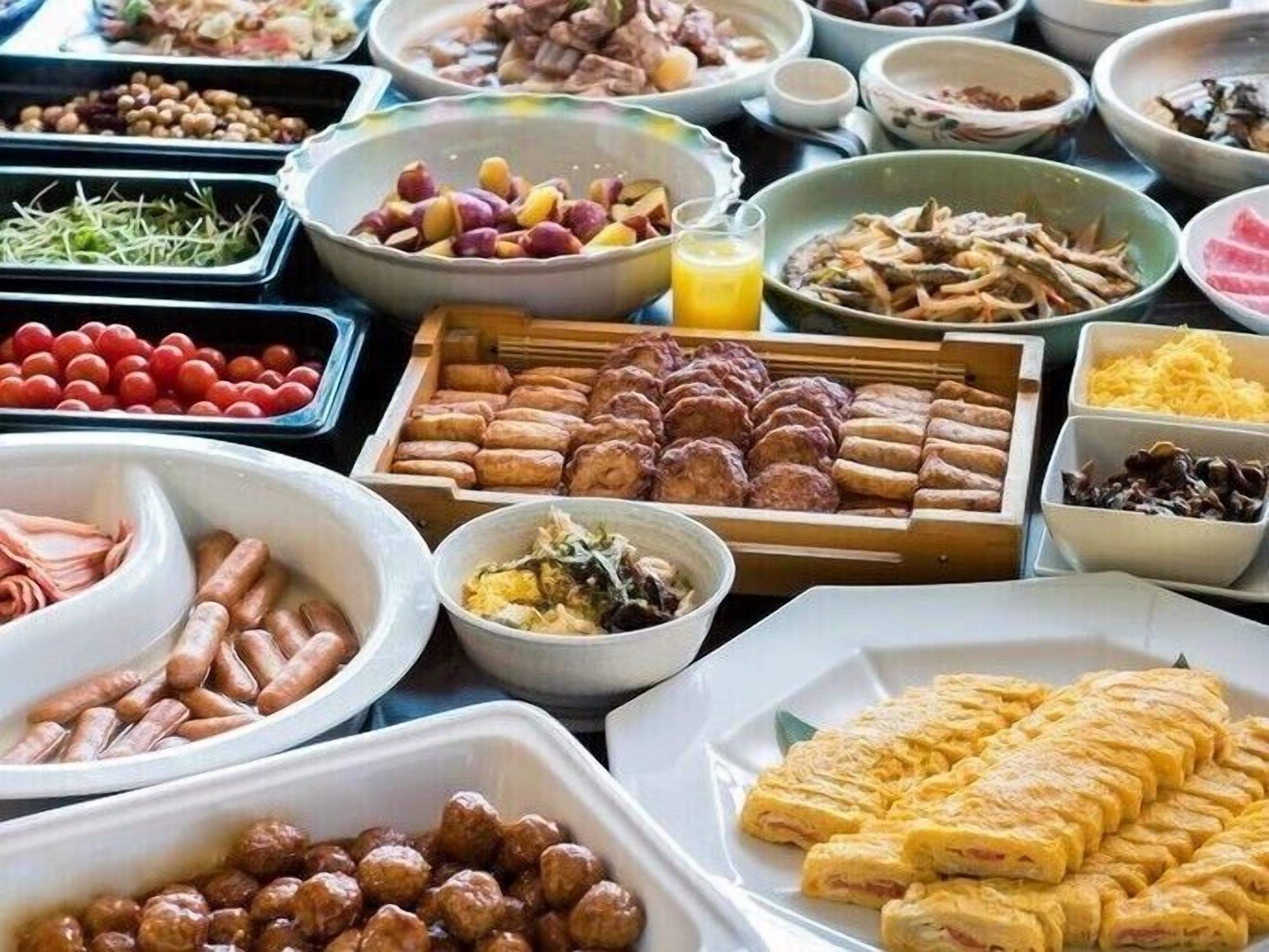 Un bufé con diversos platos, incluyendo salchichas, huevos y verduras.