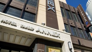 Een hotel genaamd “TAISEI ANNEX” met een opvallend verticaal bord en een modern architectuurontwerp.