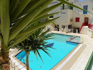 Una piscina al aire libre, sombrillas, sillones reclinables de piscina